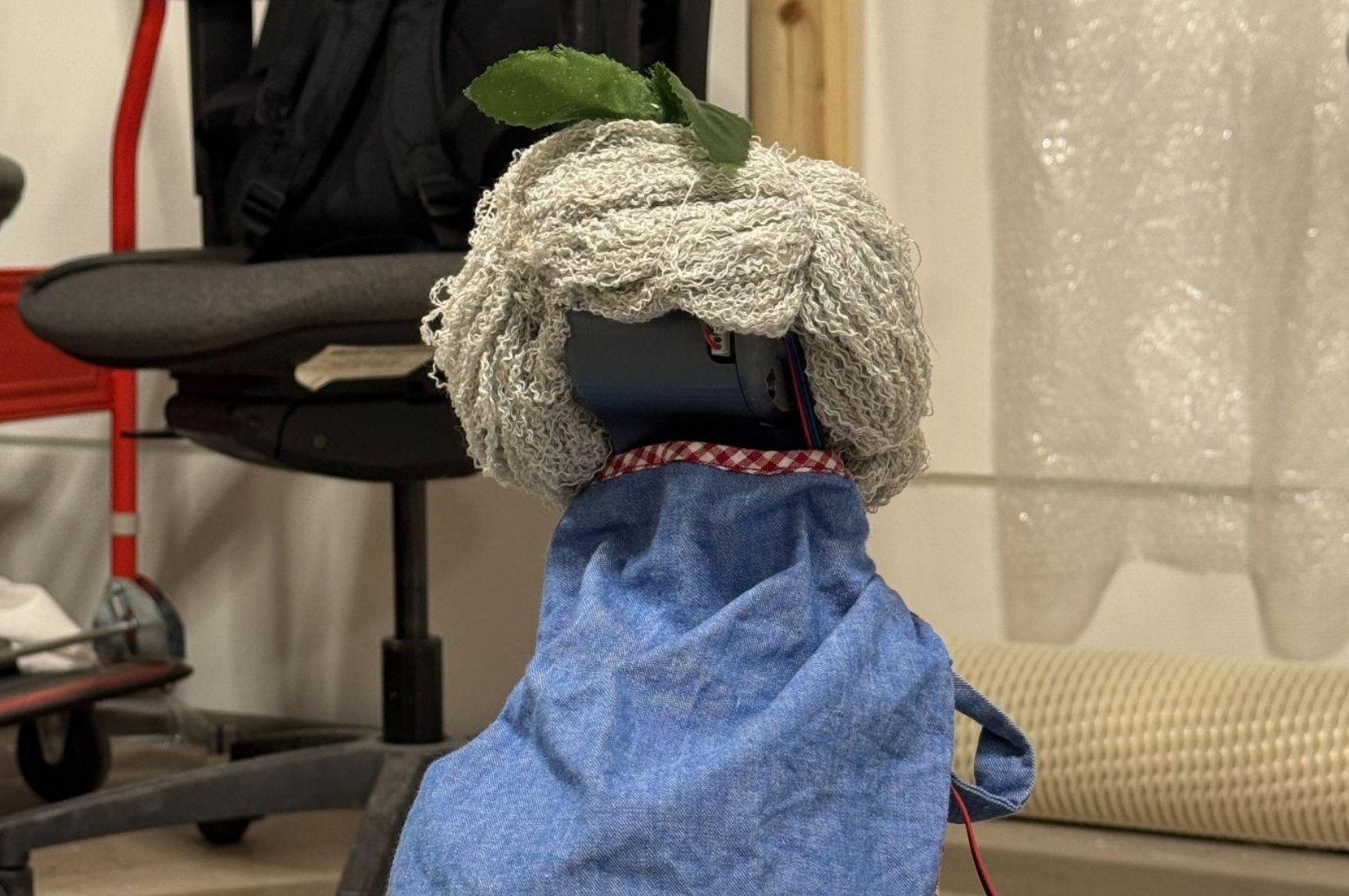 Robotic arm prototype dressed with a towel wig and leaf decoration